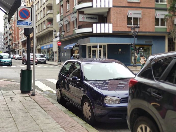 Coches estacionados en la zona azul de Oviedo, junto a un parquímetro.