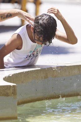 Un niño se echa agua por la cabeza para refrescarse en imagen de archivo