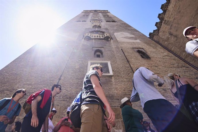 Un grupo de turistas junto a la Giralda de Sevilla.