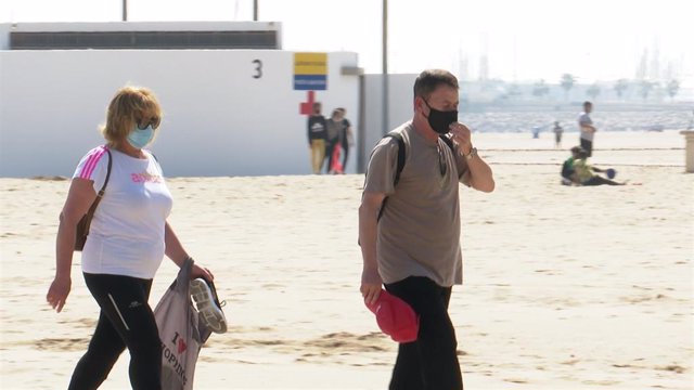 Archivo - Dos personas con mascarilla en la playa