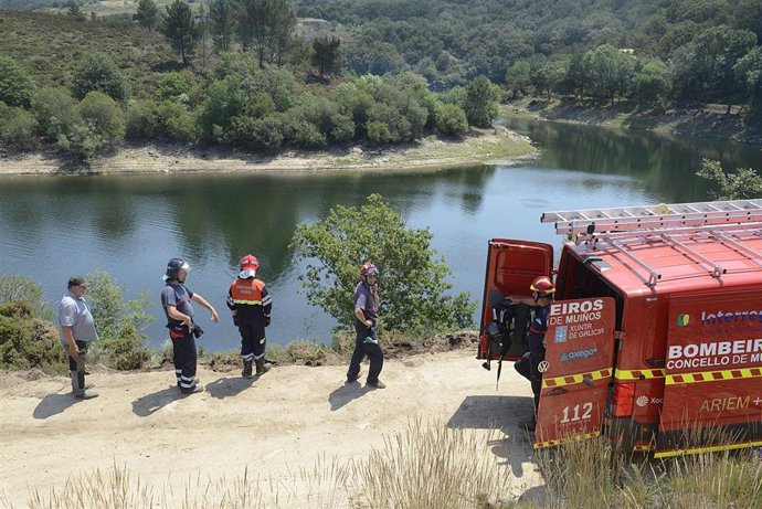 Efectivos de bomberos en el lugar donde ha caído un camión al agua tras realizar tareas de desbroce, en el embalse de As Conchas, en Muíños, Ourense, Galicia (España). El hecho se produjo cuando el camión cayó al río Limia cuando circulaba por una pista