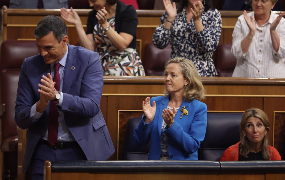 El presidente del Gobierno, Pedro Sánchez; la vicepresidenta primera y ministra de Asuntos Económicos, Nadia Calviño; y la vicepresidenta segunda y ministra de Trabajo y Economía Social, Yolanda Díaz -sentada, sin aplaudir-, aplauden.