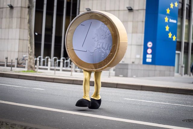 Archivo - 21 February 2022, Hessen, Frankfurt_Main: A performer dressed as a "Eurolino" in the form of a one-euro coin on legs crosses a street in front of the temporary headquarters of the German Federal Bank (Deutsche Bundesbank) in Frankfurt during fil