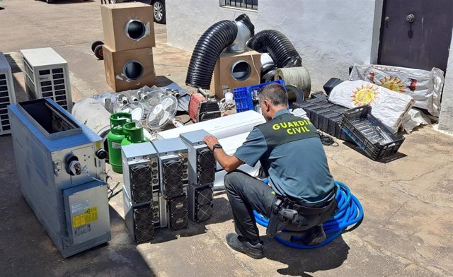 Un agente de la Guardia Civil, con la maquinaría utilizado en el taller de criptomonedas de Guillena.