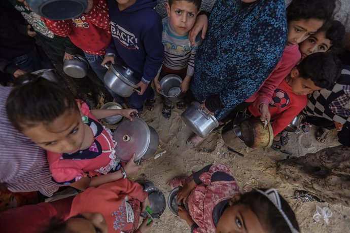 Archivo - Niños palestinos esperan a recibir comida en Gaza