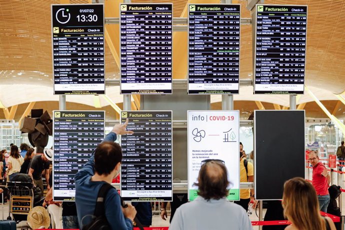 Pasajeros observan las pantallas con los vuelos de la Terminal 4 del Aeropuerto Adolfo Suárez Madrid Barajas, a 1 de julio de 2022, en Madrid (España). 