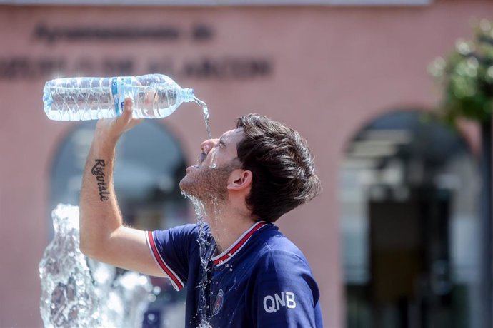 Un joven se tira una botella de agua por encima para combatir la segunda ola de calor del verano