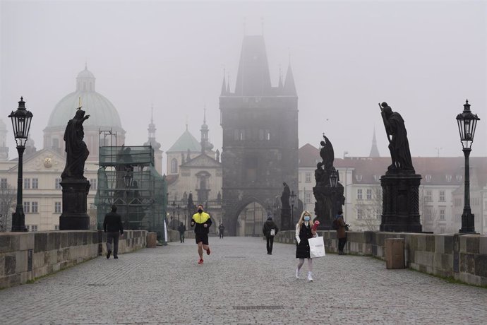 Archivo - Personas con mascarilla recorriendo un puente de Praga