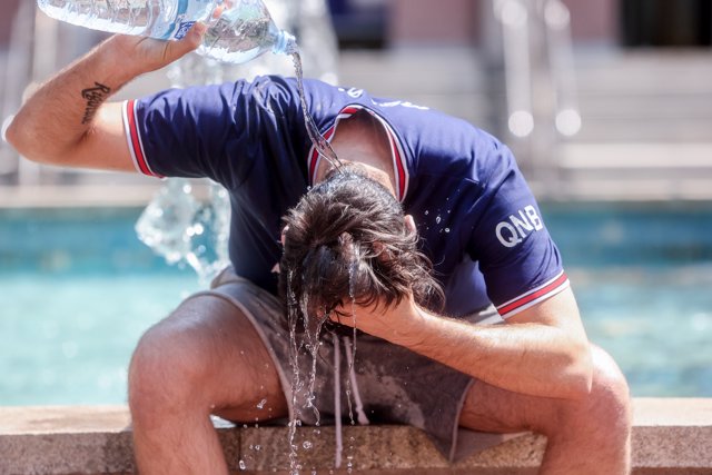 Un joven se tira una botella de agua por encima para combatir la segunda ola de calor del verano, a 12 de julio de 2022