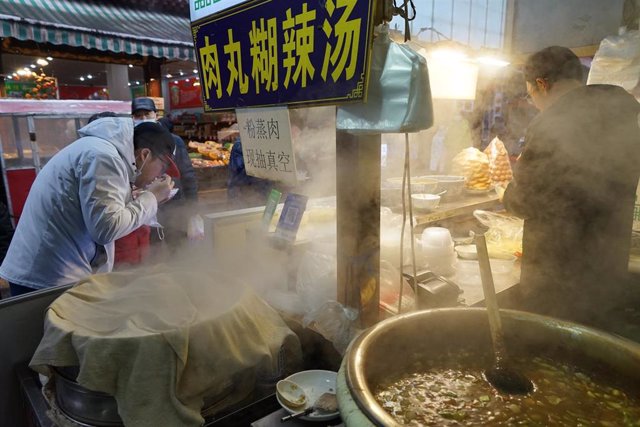Archivo - 24 January 2022, China, Xi'an: People taste food and buy new year goods in the urban area of Xi'an.