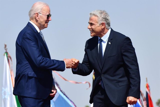 HANDOUT - 13 July 2022, Israel, Lod: Israeli Prime Minister Yair Lapid (R) receives US President Joe Biden upon landing at Ben Gurion Airport. Israel is Biden's first stop on his first tour of the Middle East since he was inaugurated president in January 