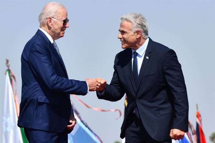 HANDOUT - 13 July 2022, Israel, Lod: Israeli Prime Minister Yair Lapid (R) receives US President Joe Biden upon landing at Ben Gurion Airport. Israel is Biden's first stop on his first tour of the Middle East since he was inaugurated president in Januar