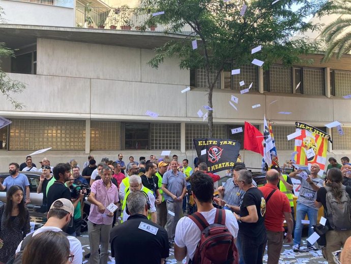 Taxistas lanzan billetes con la cara de la presidenta de la CNMC, Cani Fernández, en una protesta ante la sede del regulador en Barcelona