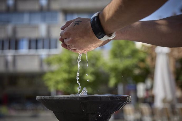Una persona coge agua de una fuente.
