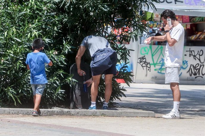 Un joven rellena una botella de agua en una fuente, a 12 de julio de 2022, en Madrid (España). 