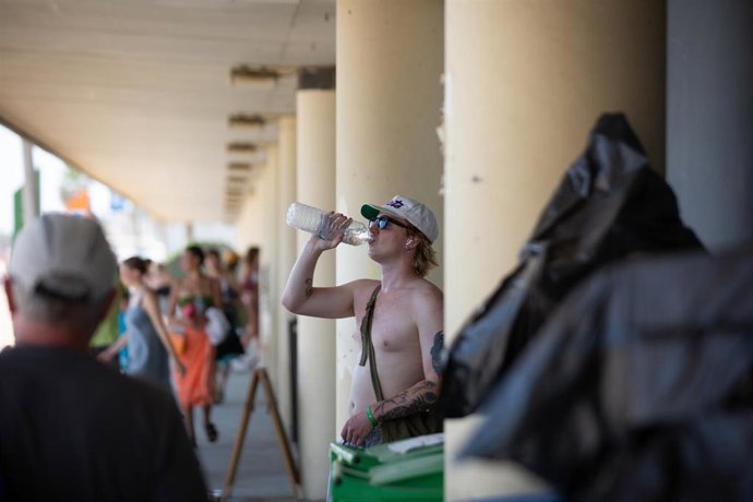 Un chico sin camiseta bebe agua en el parque de la Barceloneta, a 13 de julio de 2022, en Barcelona, Catalunya (España). La intensa y extensa ola de calor llega hoy a su momento cumbre, aunque ese pico se mantendrá durante varios días seguidos, según la
