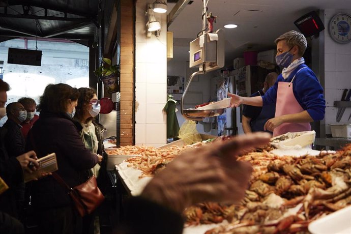 Archivo - Muchas personas delante de un puesto de venta de marisco para hacerse con algunos ejemplares antes de la cena de noche vieja en el Mercado de Triana, a 31 de diciembre de 2021 en Sevilla (Andalucía, España)