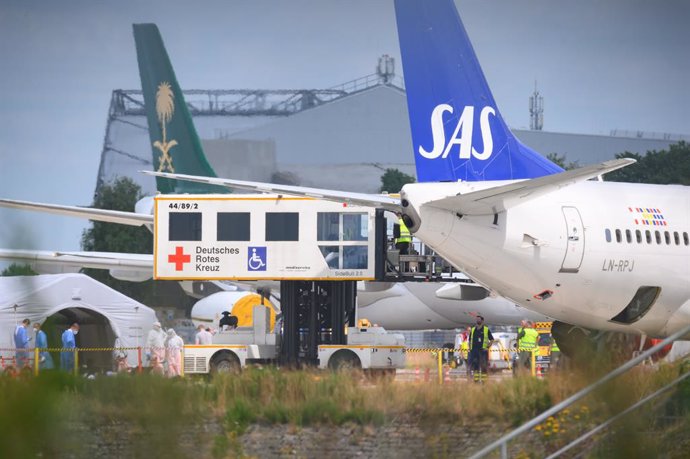 30 June 2022, Hamburg: A lift truck of the DRK (German Red Cross) stands by the SAS aircraft on the apron during the unloading of patients. An aircraft brought injured people from Ukraine to northern Germany on Thursday. Photo: Jonas Walzberg/dpa