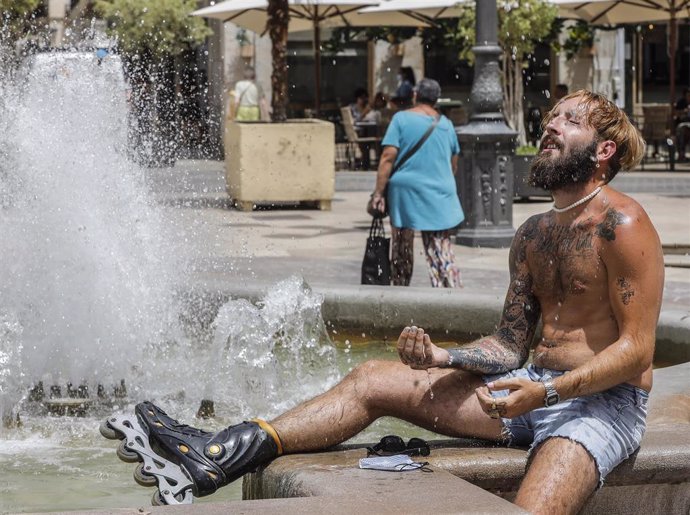 Archivo - Un hombre se refresca en una fuente del centro de Valencia para soportar las altas temperaturas