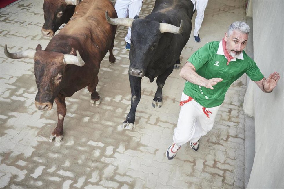 Un hombre corre durante el último encierro de las Fiestas de San Fermín 2022 con toros de Miura, a 14 de julio de 2022, en Pamplona, Navarra (España).