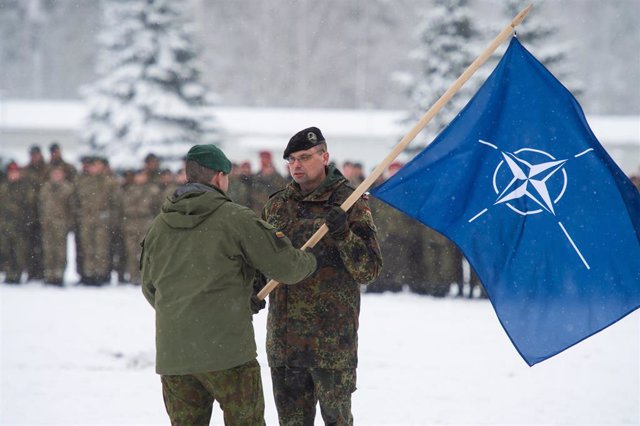 Archivo - Varios militares sostienen una bandera de la OTAN en Lituania.