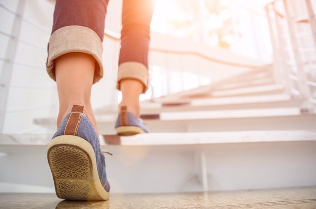 Archivo - 874231466 Young adult woman walking up the stairs with sun sport background.