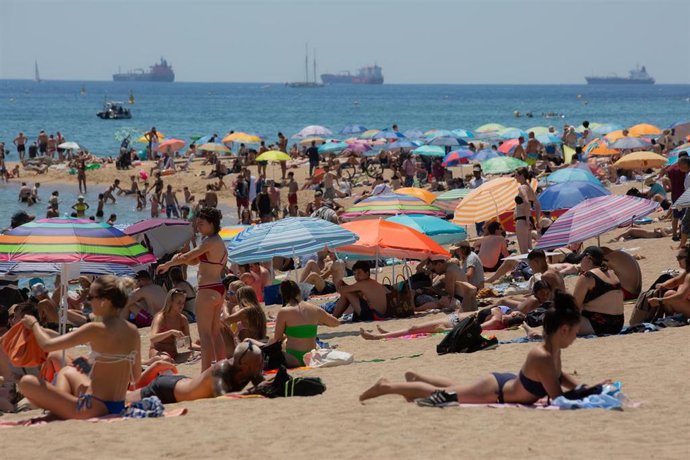Varias personas se protegen del sol en la playa de la Barceloneta, a 13 de julio de 2022, en Barcelona, Catalunya (España). 