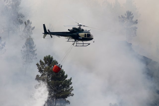 Un helicóptero sobrevuela un incendio durante las tareas de extinción a 15 de julio de 2022, en Quiroga, Lugo.
