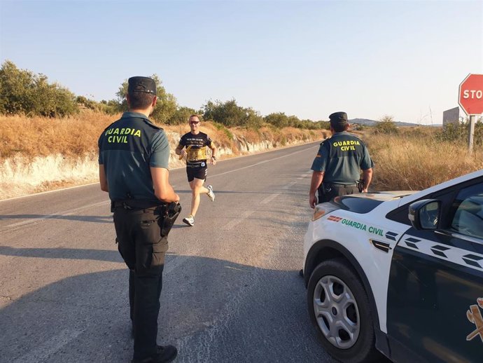 Uno de los corredores se cruza con agentes de la Guardia Civil en el reto solidario '1000 kms. Por la Sonrisa Infantil'.