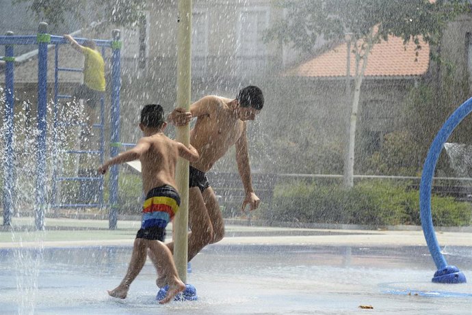 Dos personas se refrescan en unos chorros durante un día de calor en Ourense.