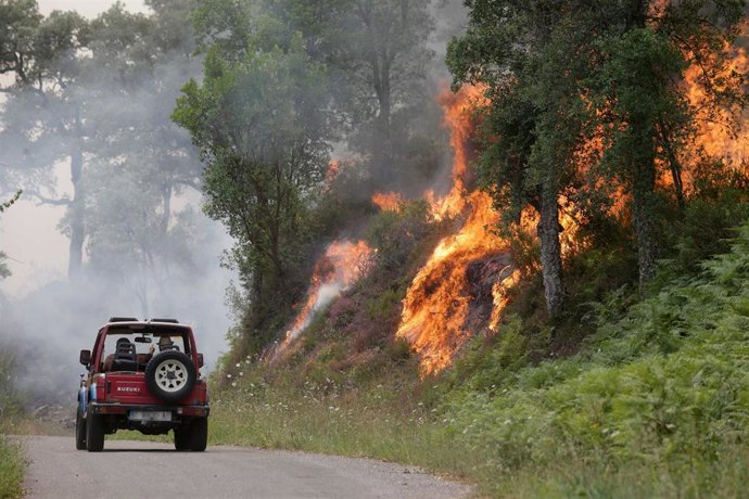 Un coche pasa cerca de las llama en un incendio, a 15 de julio de 2022, en Samos, Lugo, Galicia (España).