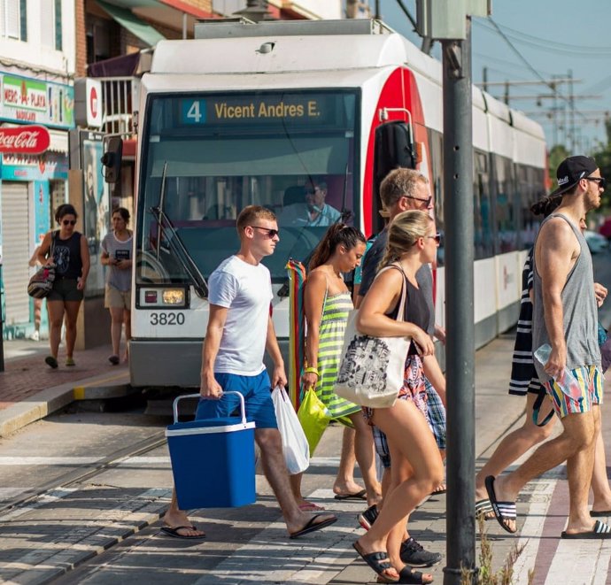 Viajeros junto al tranvía en dirección a la playa