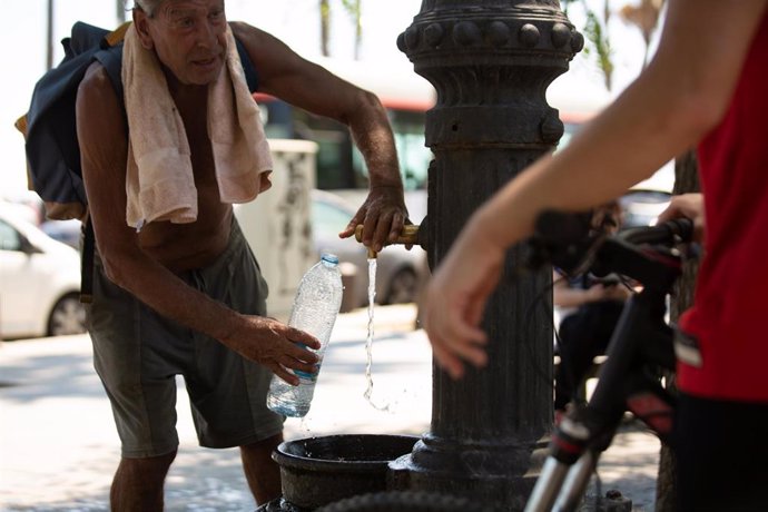 Un hombre rellena una botella de agua en una fuente