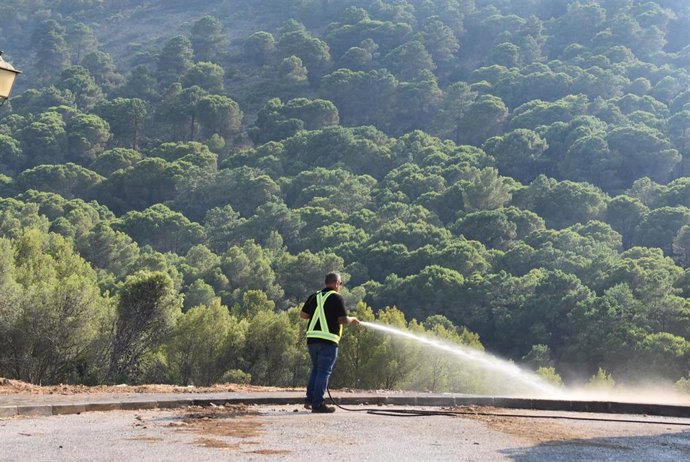 Una persona con una manguera en la zona de Jarapalos, en Alhaurín de la Torre, afectada por el incendio forestal en la Sierra de Mijas que está estabilizado desde el domingo 16 de julio por la tarde