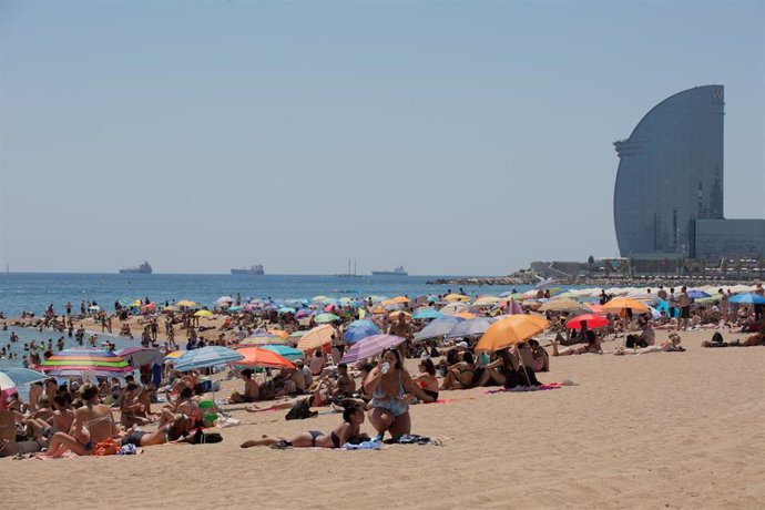 Varias personas se protegen del sol en la playa de la Barceloneta, en una imagen de archivo.
