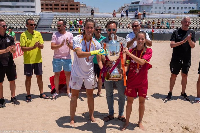 José Manuel Páez, Concejal de Deportes del Ayuntamiento de Cádiz, muestra el trofeo de la final del fútbol playa femenino junto a las jugadoras