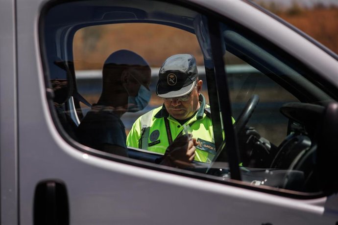 Un agente de la Guardia Civil pide la documentación al conductor de un vehículo durante un control en la autovía A-5,