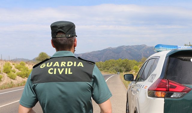 Un agente de la Guardia Civil junto a un vehículo en una carretera.  (Foto de archivo).