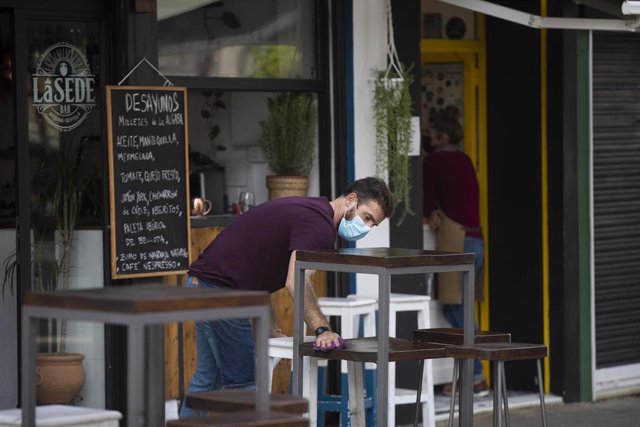 Archivo - Un camarero limpia una mesa alta de la terraza de un establecimiento del centro de Sevilla.