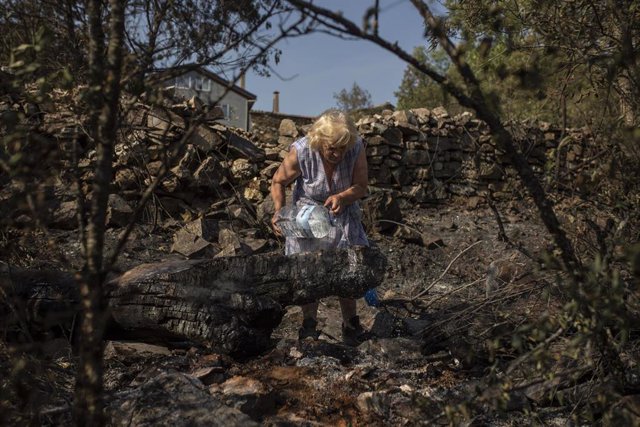 Una mujer echa agua en una zona vegetal afectada por el incendio de Losacio, a 19 de julio de 2022, en Ferreras de Abajo, Zamora, Castilla y León (España). Con 10.000 hectáreas abrasadas en las primeras cuatro horas, dos fallecidos y más de una decena de 