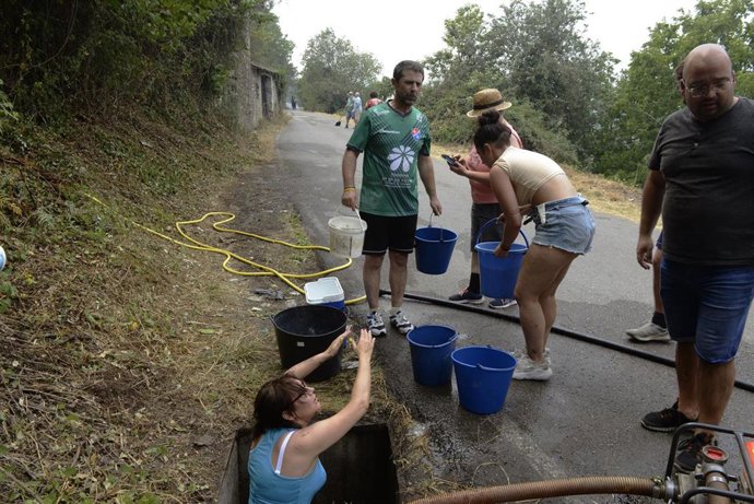 Vecinos preparan cubos de agua para trabajar en la extinción del incendio en O Barco.  