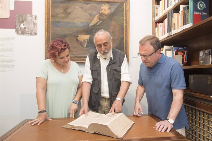 Sofía Avellanas, Venancio Díaz y José Domingo Dueñas ojean el libro donado al Espacio Joaquín Costa del IEA.