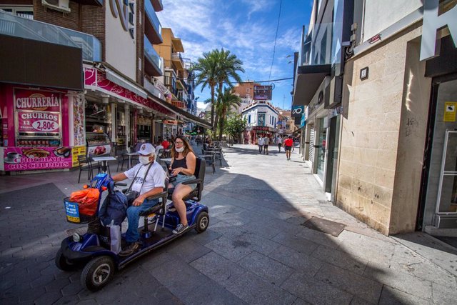 Archivo - Dos personas pasean en un scooter eléctrico por Benidorm durante el Día Mundial del Turismo 2020