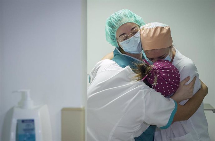 Archivo - Tres enfermeras se abrazan por el traslado a planta de un paciente ingresado a UCI