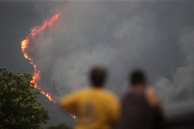 Dos personas observan un incendio, a 15 de julio de 2022, en Quiroga, Lugo, Galicia (España). Permanece activo desde las 20,29 horas de este jueves un incendio en la parroquia de Outeiro, que según las últimas estimaciones afecta a una superficie de 200 h