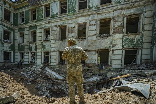 Archivo - Un soldado de Ucrania ante un cráter por el impacto de un proyectil ruso en un instituto en la localidad de Kostiantinivka, en la región de Donetsk