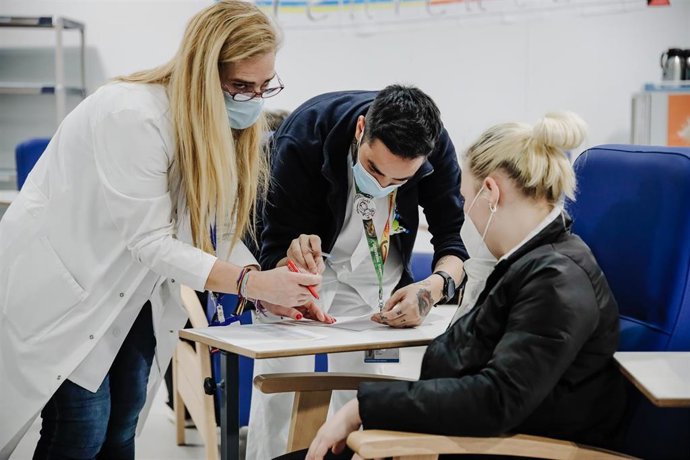 Archivo - Dos sanitarios registran a una mujer refugiada, a su llegada al Hospital Isabel Zendal, a 16 de marzo de 2022, en Madrid (España). Este grupo de personas ucranianas ha llegado a España gracias al convoy humanitario de la Fundación de La Asocia