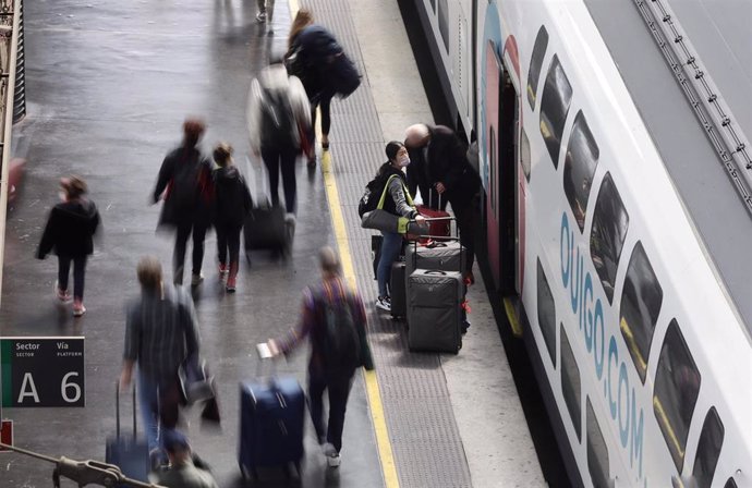 Archivo - Varias personas, con maletas y mascarillas, en el andén antes de coger un tren