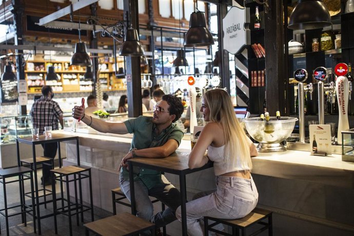 Archivo - Dos personas sentadas en una mesa haciéndose una foto durante la reapertura del Mercado de San Miguel, a 2 de julio de 2021, en Madrid, (España).