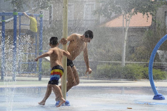 Dos personas se refrescan en unos chorros durante un día de la segunda ola de calor de verano en España, en una imagen de archivo.